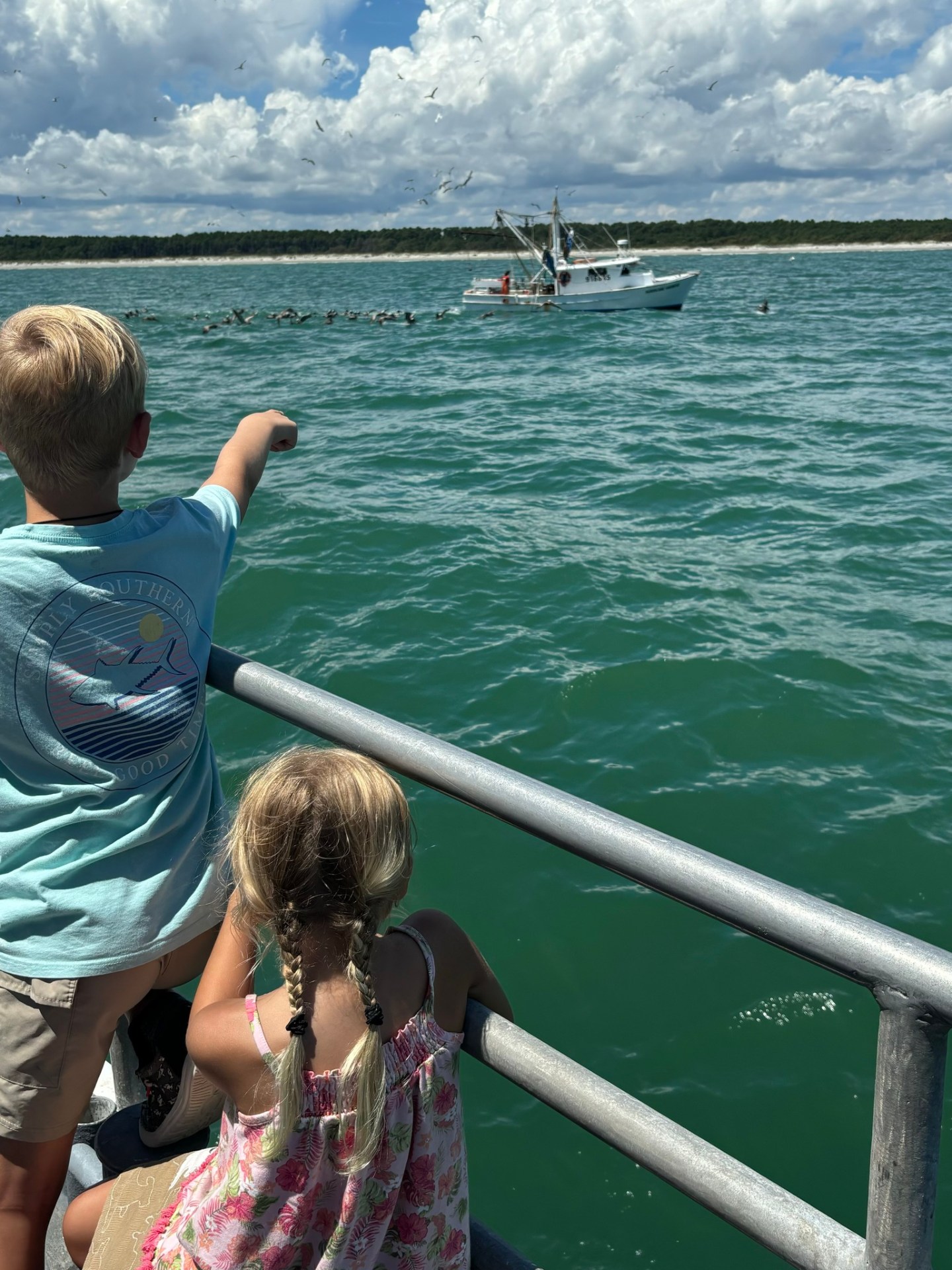a group of young children sitting next to a body of water